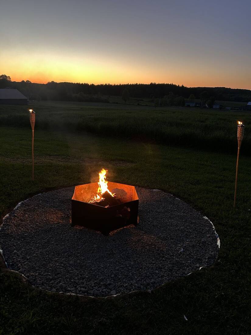 Gravel fire pit pad at sunset with tiki torches